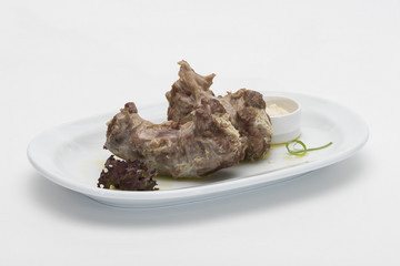 Turkey necks, served with horseradish puree, placed on white plate, light background, isolated