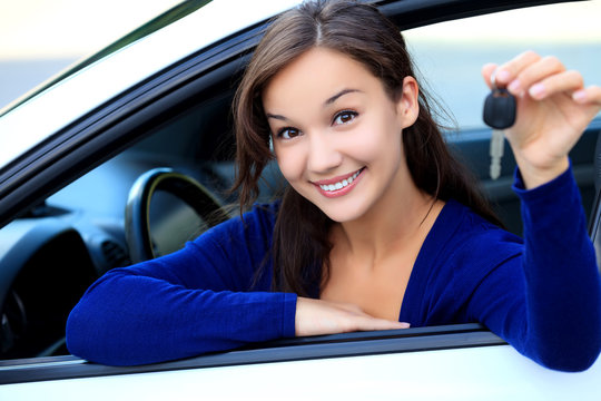 Beautiful young smiling happy girl shows the car key in her hand