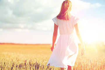 young woman in white dress walking along on field