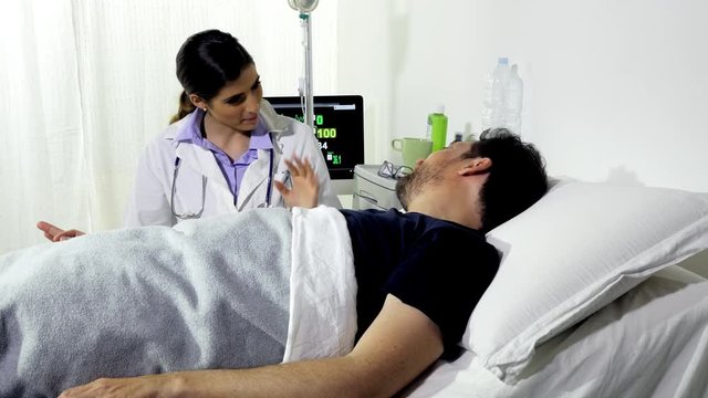 Man lying in bed in hospital laughing with female doctor