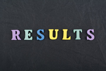 Obraz premium RESULTS word on black board background composed from colorful abc alphabet block wooden letters, copy space for ad text. Learning english concept.
