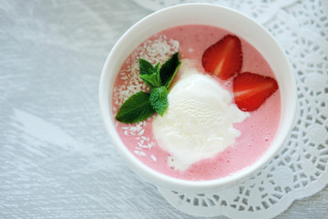 Cold creamy strawberry soup with a scoop of ice cream and mint