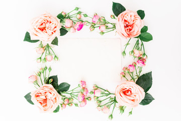 Frame of pink roses, buds and leaves with paper card on white background. Flat lay, top view. Floral background.