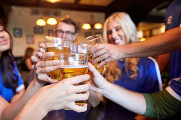football fans clinking beer glasses at sport bar