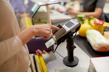 woman entering pin code at store cash register