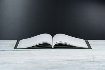Open book on wooden deck table and black board background. Back to School. Education concept with copy space for your ad text.