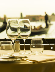 closeup of empty wine glasses in Venice, Italy. Romantic scene with gondola and couple in background
