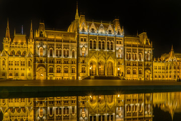 Fototapeta premium ungarisches beleuchtetes Parlamentsgebäude spiegelt sich in Wasserfläche