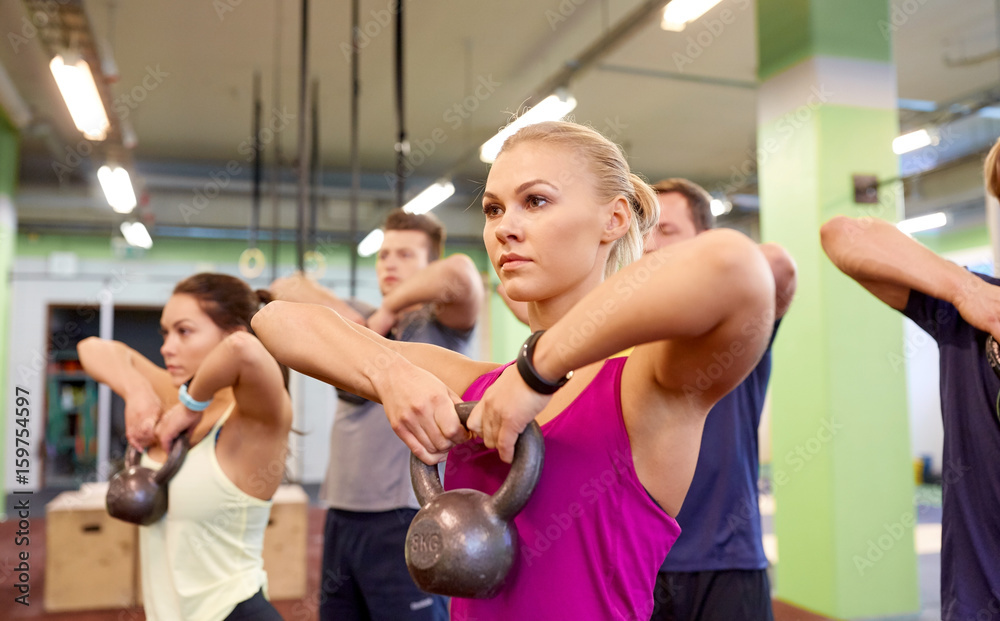 Wall mural group of people with kettlebells exercising in gym