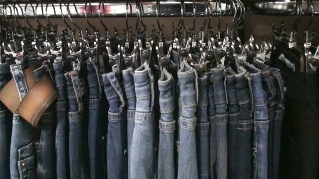 Jeans hanging on hangers on the rack in the clothing store. HD 1920x1080 Video Clip