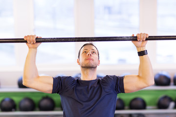 Naklejka premium man exercising on bar and doing pull-ups in gym