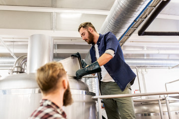 men working at craft brewery or beer plant
