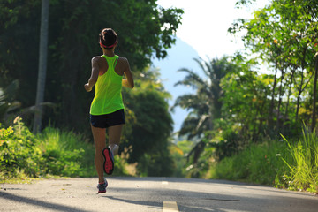 healthy lifestyle woman running at morning tropical forest trail