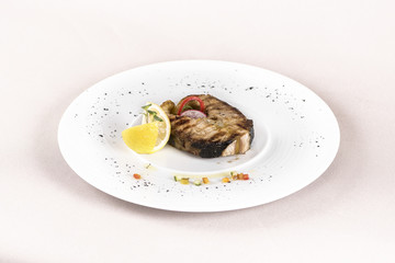 Grilled carp, served with lemon and decorated with radish and fresh leafs, light background, isolated