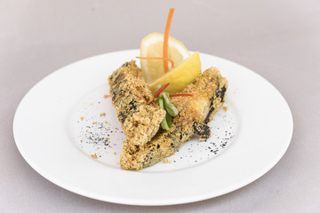 Grilled carp, served with lemon and decorated with radish and fresh leafs, light background, isolated