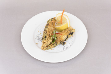 Grilled carp, served with lemon and decorated with radish and fresh leafs, light background, isolated