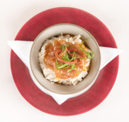 Beans puree with sweet onion and tomato sauce, served in a bowl on a red and white plate, decorated with herbs, light background, isolated