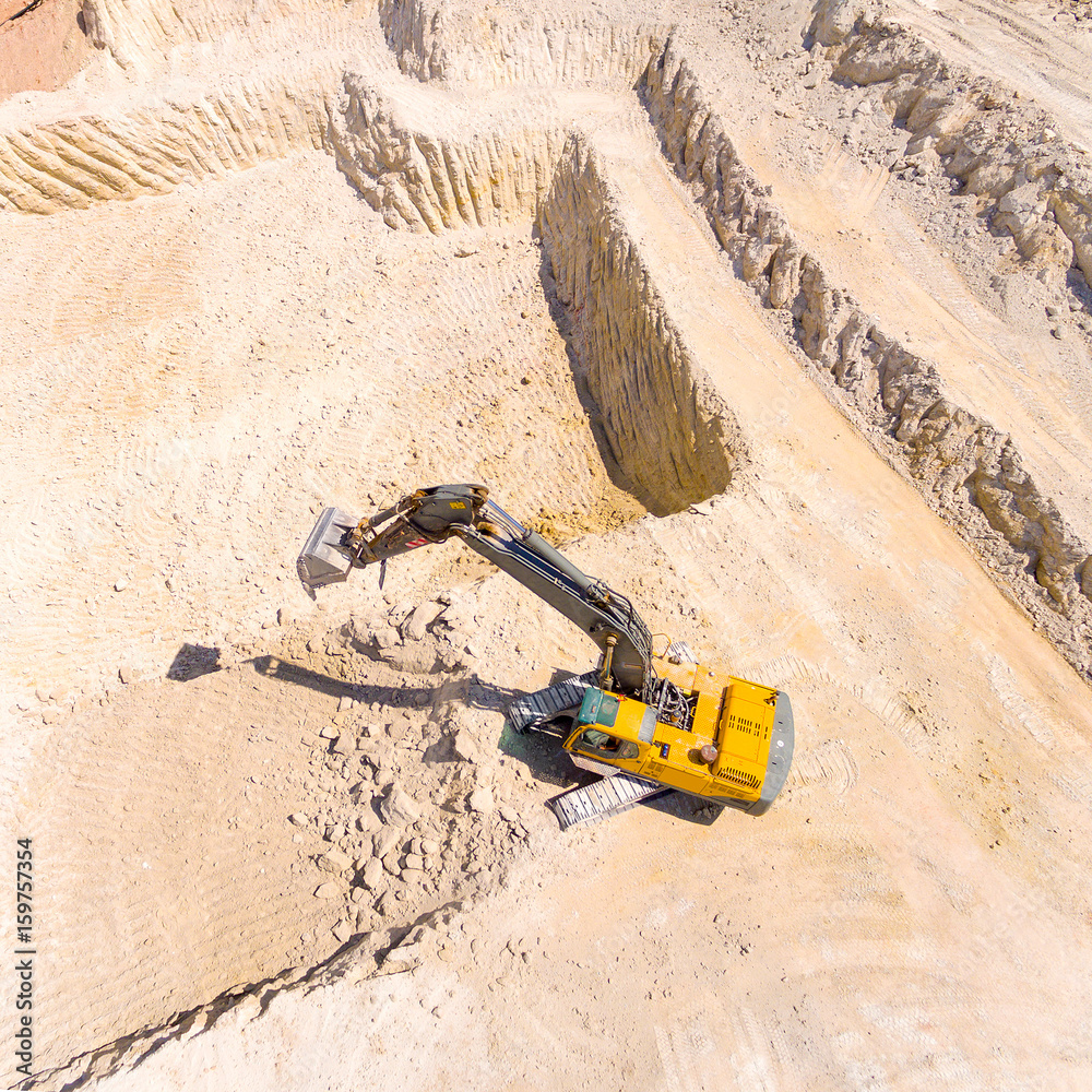 Wall mural Aerial view of a excavator in open cast mine or on construction site. Heavy industry from above. Industrial background from drone.  - Wall murals