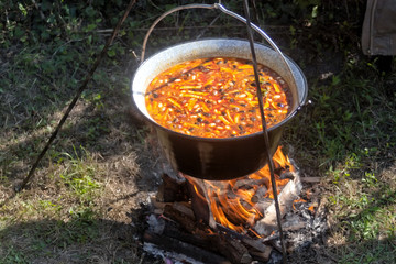 Cooking bean goulash in a caldron on open flame