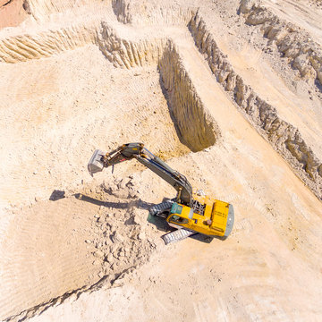 Aerial view of a excavator in open cast mine or on construction site. Heavy industry from above. Industrial background from drone. 