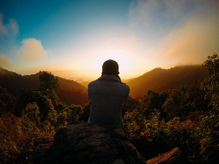 Naklejka na ściany i meble Alone man on the top of the mountains. He shooting cloudy sky and colorful sunrise.