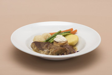 Baked beef marrow with vegetables, decorated with purple leafs, placed on white plate, light background, isolated