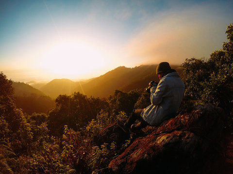 Alone man on the top of the mountains. He shooting cloudy sky and colorful sunrise. © Gittipong