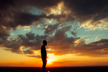 Silhouette of a man into sunset sky clouds