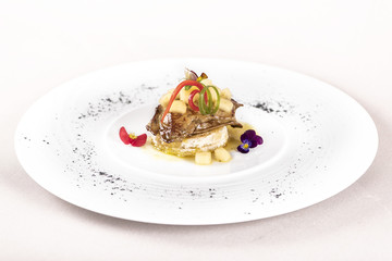 Luxurious dish with duck liver, pineapple and mango pieces, sweet sauce, placed on toasted bread, decorated with eatable flowers and red and green leafs, placed on white plate, light background, isola