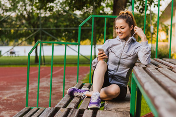 Young smiling woman using smartphone sitting on bench in park.