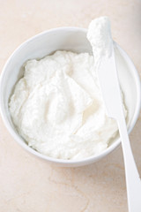 Fresh ricotta cheese in bowl with knife 