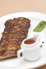  Grilled rib pork with barbecue sauce, placed on white plate, light background, isolated