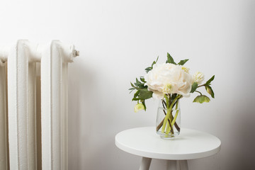 white peony flowers on coffee table in white room interior