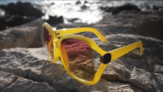 beautiful beach scene in croatia with yellow sunglasses on the rocks 