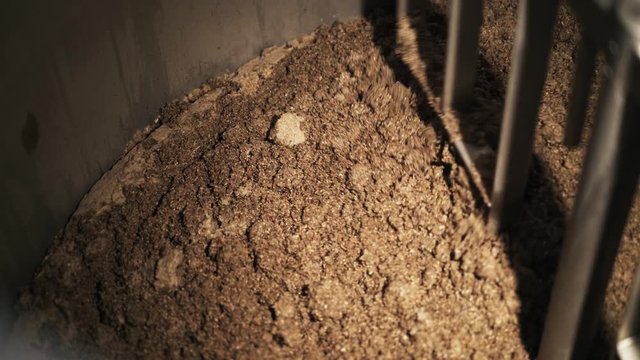 Top view of malt being stirred by a machine in a custom beer brewery cask. Handheld real time medium shot