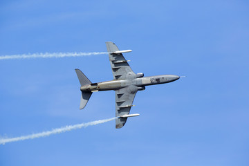 Fototapeta na wymiar Jet fighter flying with white smoke against a blue sky.