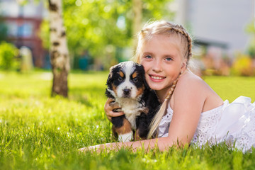 Little girl with a berner sennenhund puppy, outdoor, summer