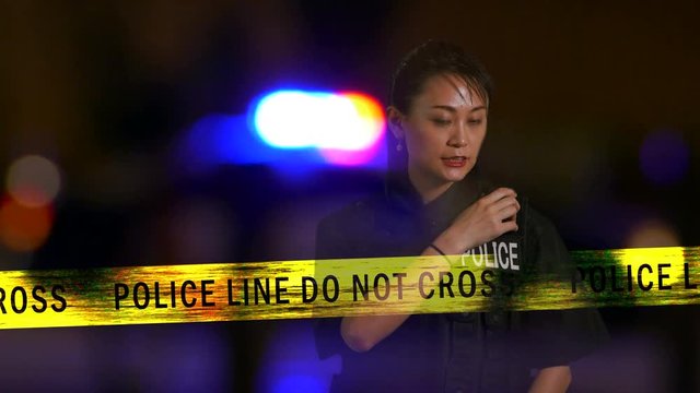 Asian American  female police officer calling in on radio from crime scene, Multiple exposure