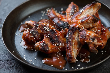 Close-up of grilled chicken wings served with sesame seeds and sauce, selective focus