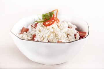 Simple tomato and cheese salad, decorated with green and red leafs, placed on a white plate, light background