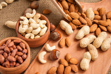 Almonds, cashew, walnuts and hazelnuts in wooden bowls on wooden and burlap, sack background