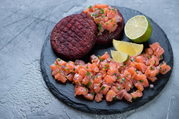 Stone slate tray with salmon tartar and beetroot cutlets, selective focus, horizontal shot