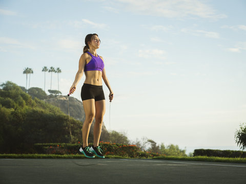 Young woman jumping rope in park