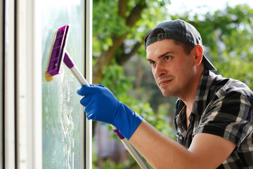Young man cleaning Window with mop. Window washer. Professional cleaning company.