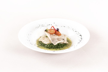 Perch fillet with spinach, sauce and tomato, decorated with eatable flowers and red leafs, placed on white plate, light background, isolated