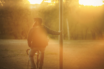 Bearded guy on fix bike. A brutal young man with a huge beard in sunglasses and a cap in the woods...