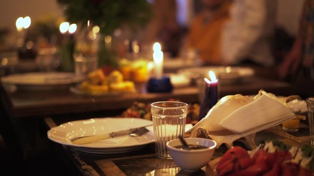 Close up of a beautifully laid table in a luxury restaurant. Candle light. Romance. Blurred people in the background. Handheld real time close up shot