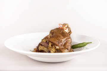Knuckle of pork with sauerkraut and hot chili, white plate, light background, isolated