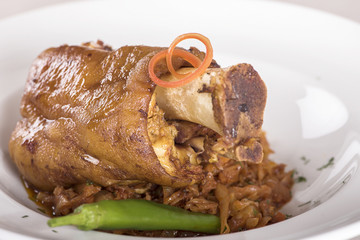 Knuckle of pork with sauerkraut and hot chili, white plate, light background, isolated