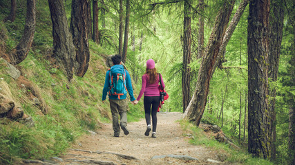 Fototapeta premium A couple hikers Hiking with backpacks walk along a beautiful mountain area holding hands . The concept of active rest. Switzerland 2017